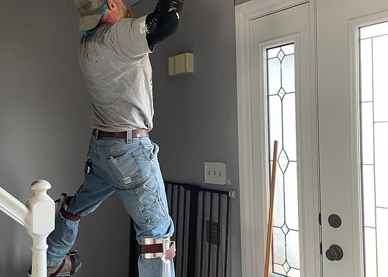 Worker on drywall stilts finishing a ceiling