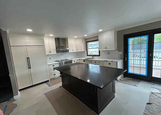 Large kitchen with white cabinetry, a dark island, stainless range hood and paneled refrigerator